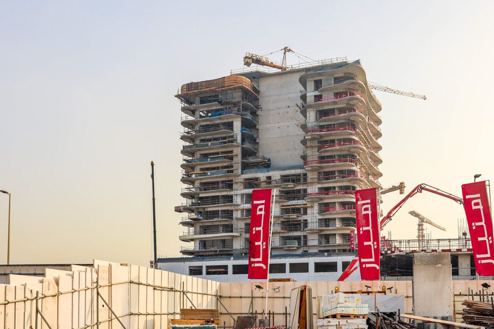 Beach Walk Iii By Imtiaz A construction site featuring a partially completed multi-story building with cranes and large banners in front.